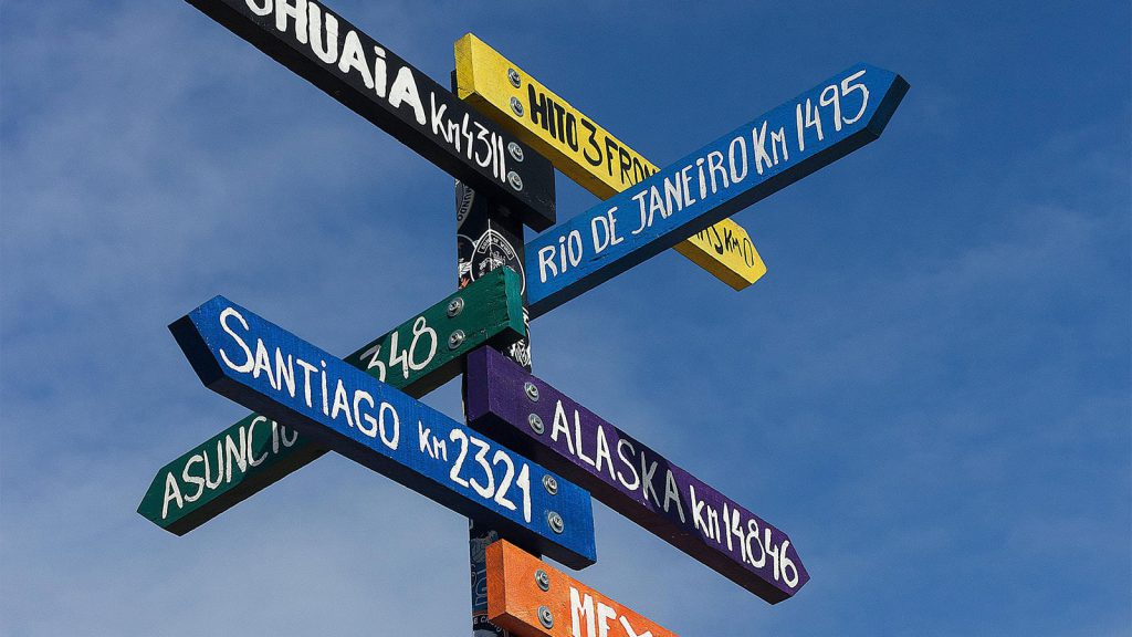 A photo of multiple wooden signposts against a blue sky